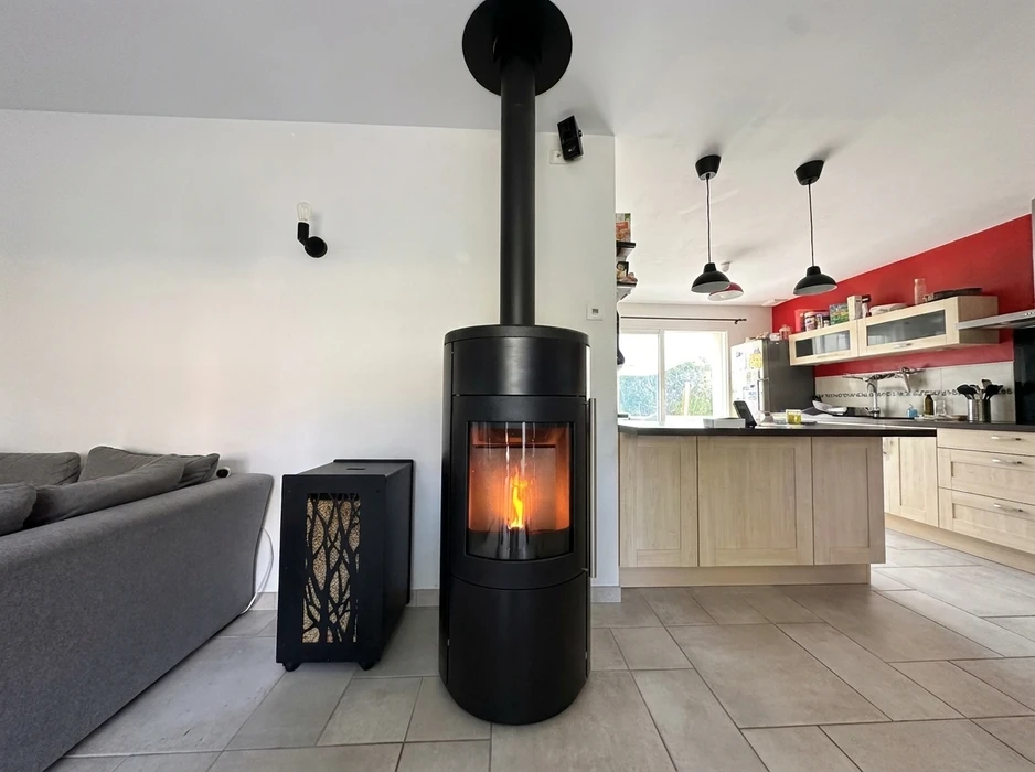 Poêle à granulés (pellets) noir mat installé dans un intérieur moderne, mur en pierre apparente en fond