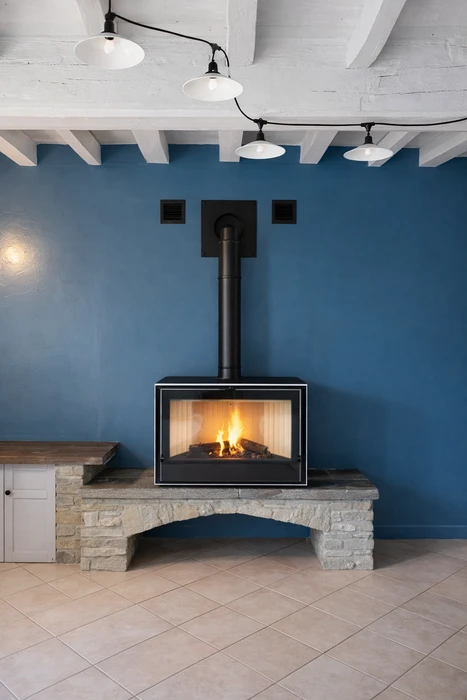Poêle à granulés cylindrique noir mat en fonctionnement, installé dans un salon carrelé