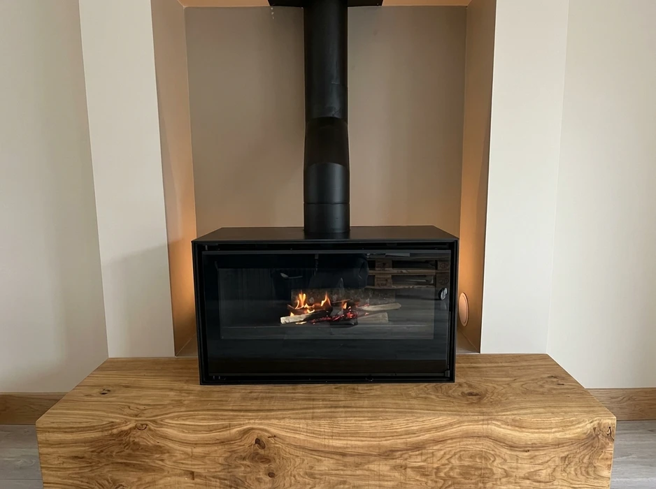 Poêle à bois suspendu de design cylindrique noir mat, vitré panoramique incurvé, avec feu actif visible
